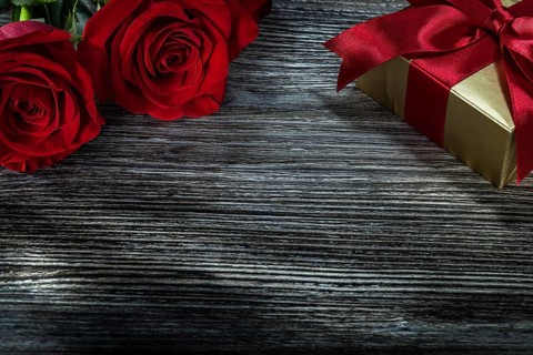 Golden gift box red roses on wooden board