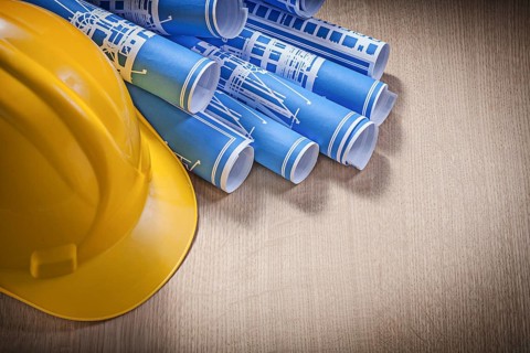 Blue rolled blueprints building helmet on wooden board construction concept