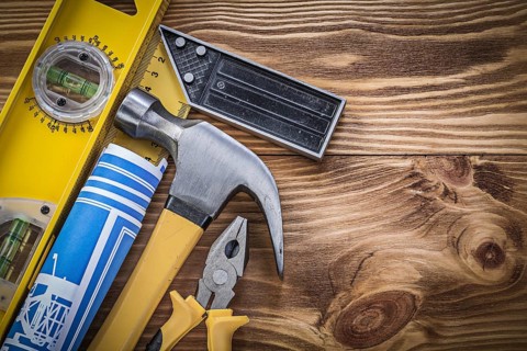 Blue blueprints construction level square ruler claw hammer pliers on wooden board