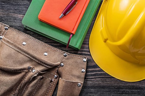 Tool belt notepads pen safety building helmet on wooden board construction concept