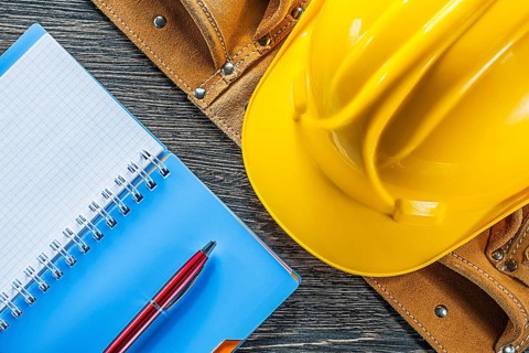 Notebook pen tool belt building helmet on wooden board