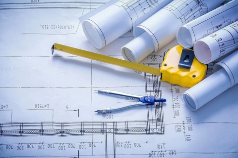 Rolled blueprints compass and yellow tapeline