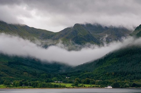 Idyllic mountain landscape with morning early fog covering the peaks at Fort Williams, Glencoe area