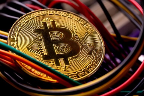 Virtual cryptocurrency money Bitcoin golden coin on a computer printed circuit board PCB surrounded