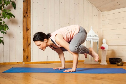 An image of a pretty woman doing yoga at home - crow