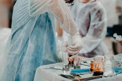 Medical staff in protective clothing operating a syringe on a sterile table