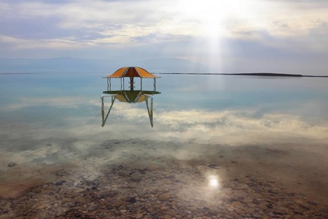 Medical beach on the Dead Sea, Israel. Round gazebo in the water near the water's edge. Cloudy sky