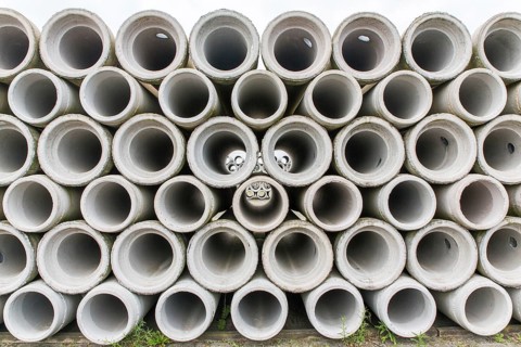 Pile of concrete sewer pipes on concrete plant grounds