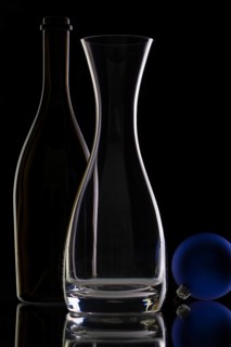 The bottle of wine, glass carafe and Christmas decoration on a black glass desk