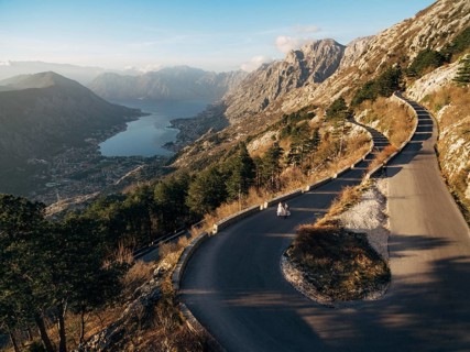 Bride and groom are walking along a high-mountain asphalt road over the bay.