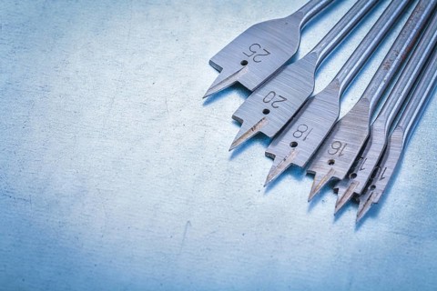 Metal spade bits for drilling wood on metallic background construction concept