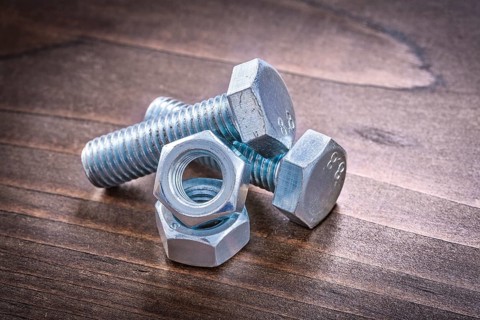 Couple of steel bolt details and screw nuts on vintage brown wooden board construction concept