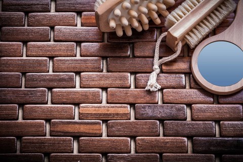 Wood massager looking-glass and peeling brush on textured wooden mat sauna concept