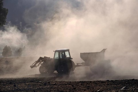 Tractor spreading lime with a fertiliser spreader, West Coast, New Zealand, Oceania