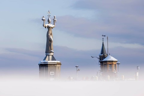 A large statue of Imperia and a small tower rise out of a misty winter landscape, Constance