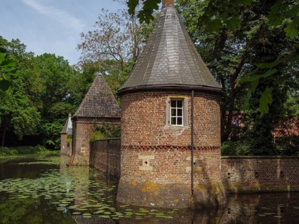 Brick building with towers reflected in a pond covered with water lilies, ochtrup, münsterland,