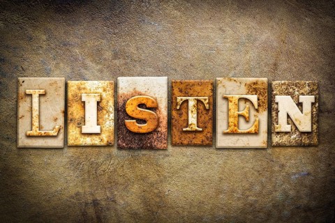 The word LISTEN written in rusty metal letterpress type on an old aged leather background
