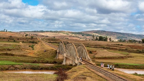 Malagasy people from the countryside cross a railroad bridge on the way to work and school on May
