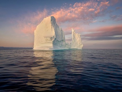 Large glaciers in the bay by the rocky shore in the light of the setting sun