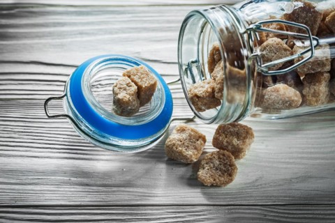 Glass with brown sugar on wooden board