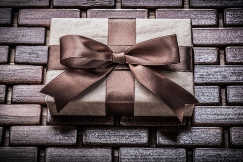 Wrapped giftbox with ribbon on wooden wicker matting holidays concept