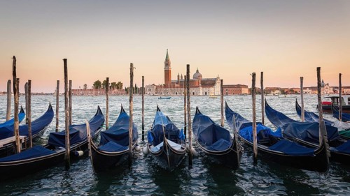 Gondolas moored docked on water in Venice. Gondoliers sailing San Marco basin waterway. San Giorgio