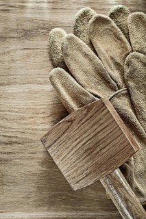 Pair of leather protective gloves Wooden hammer on wooden board '
