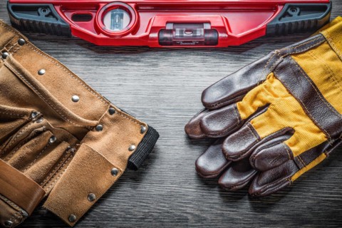 Construction level protective gloves leather tool belt on wood board
