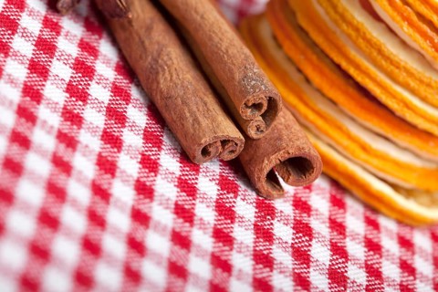 Slices of dried orange and cinnamon sticks on a chequered cloth