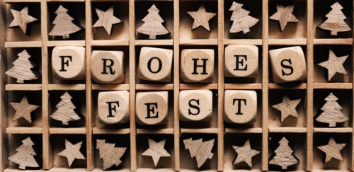 Wooden box with the German words Merry Christmas and small tree and star shapes
