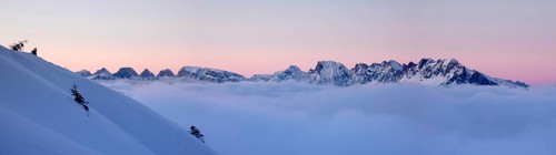 panorama winter mountain landscape at sunset with snow slope and cloud cover in the foreground in
