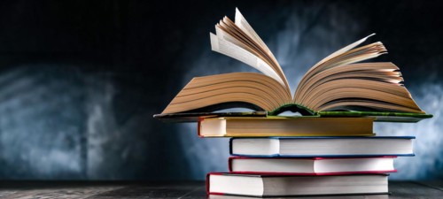 A composition with an open book lying on a stack of other books