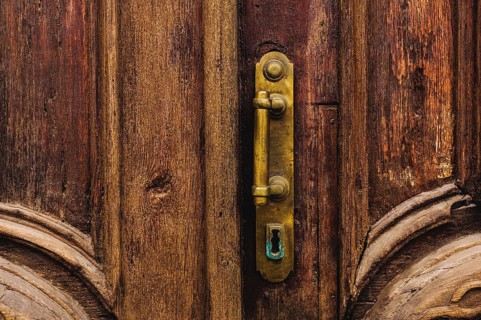 Vintage background. Brass-made old handle with Elements of an carved wooden door decorated with