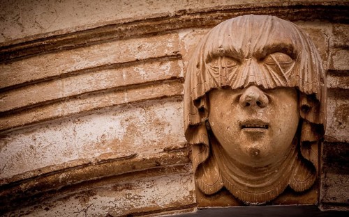 Gothic detail. Young woman portrait at the entrance of a 200 years old building in Ciutadella town,