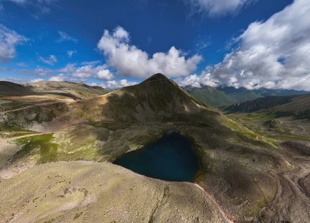 Aerial view of high mountain glacial lake and snow capped mountain peaks. Landscape of an alpine