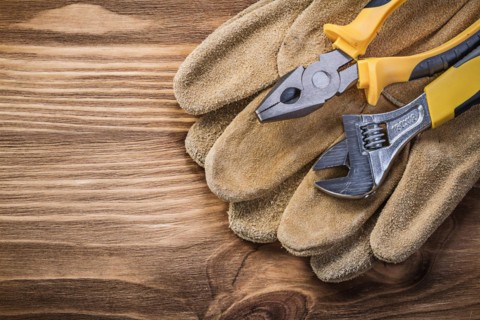 Protective gloves adjustable spanner pliers on wooden board construction concept