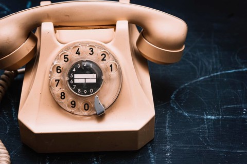 Close-up of a beige vintage rotary phone on a dark surface, evoking a sense of nostalgia