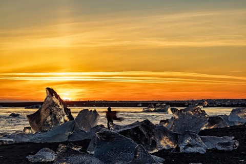 Dancing girl in diamond beach in Vatnajokull National Park at sunset, Iceland, Europe