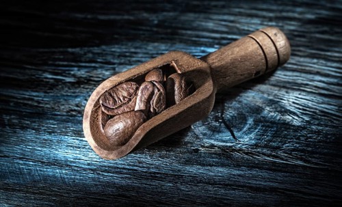 Coffee beans in scoop on wooden board