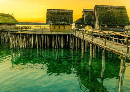 Fishing huts made from wood, clay and thatched roof, suspended on stilts over a lake water, with