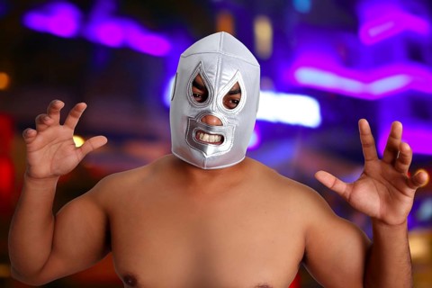 Mexican wrestling mask silver fighter with aggresive gesture night blurred lights