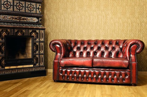 Old Red Genuine Leather Sofa Near The Fireplace
