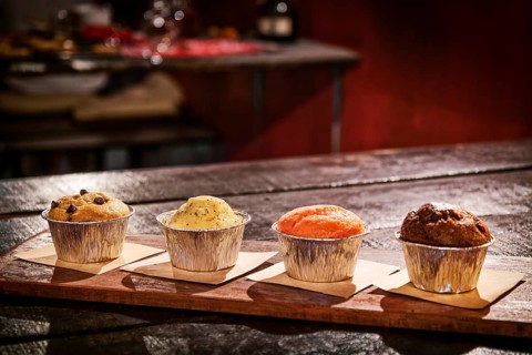 Mixed freshly baked muffins on table in cozy coffeeshop interior