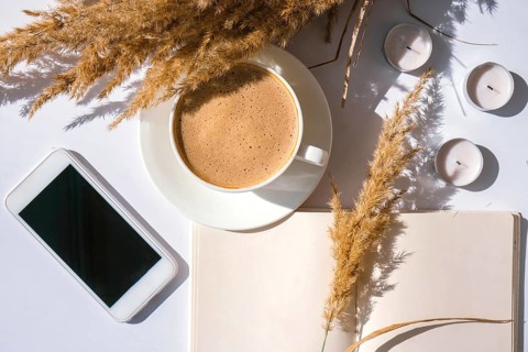Pampas grass and white cup with coffee. Mobile phone with black screen. Checking social media