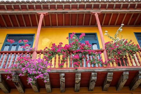 Low angle view of colorful colonial house facade with a flower decorated balcony, Cartagena,