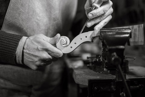 Close-up of a craftsman delicately carving a violin scroll with precision