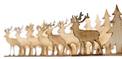 Deer figure sawn out of wood with dark edges and wooden fir trees cut out on white