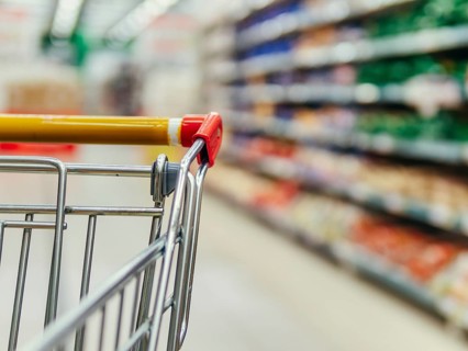 Shopping cart in supermarket. Part of shopping trolley in supermarket aisle. Blurred shelves in