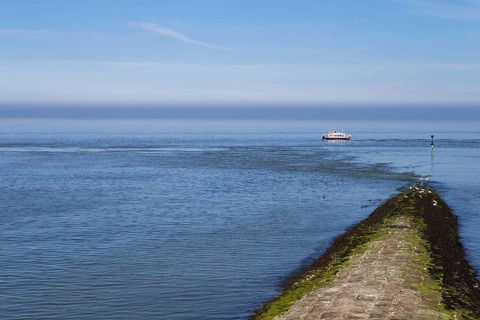 The photo shows a jetty with a survey vessel by day on the island of Baltrum