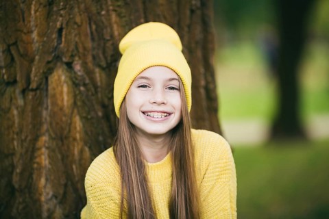 Cute teenage girl with braces smiling happily dressed in bright yellow clothes outdoors. Cute and